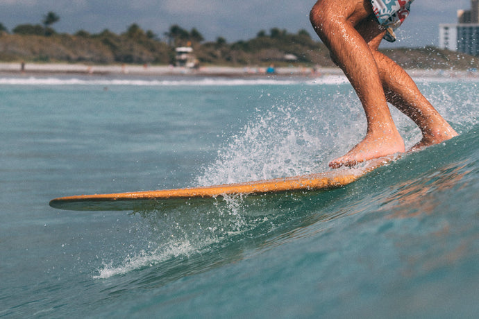 Close-up of a surfer's feet on a longboard with the Jupiter, Florida beach behind. Photo: Greg Panas
