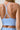 Close-up back view of a woman wearing a light blue sports bra with crisscross racerback straps.