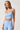 A woman modeling a light blue athletic set consisting of a ruched sports bra.