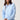 A woman modeling a light blue long-sleeve cropped hoodie.