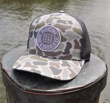 Duck camo UV performance hat featuring the original Blueline logo patch, designed for boating, fishing, golf, and outdoor adventures in Jupiter, Florida.