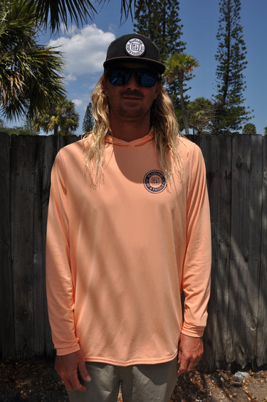 Person wearing coral OG Logo Hooded UV Sun Shirt from Blueline Surf & Paddle Co. designed for sun protection, fishing, boating, paddling, and coastal outdoor adventures in Jupiter Florida.