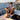 Man wearing OluKai ʻAhi Kai sandals while relaxing aboard a boat at sunset