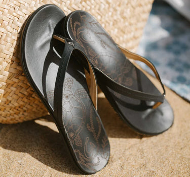 Women's OluKai Honu Black leather sandals styled for beach vacations, travel, and everyday coastal wear.