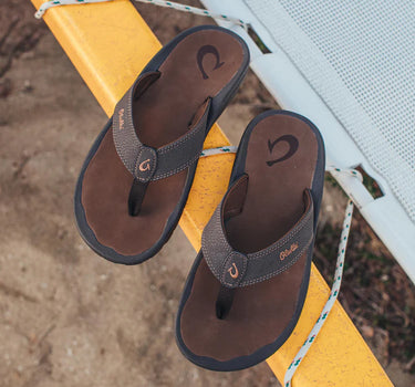 OluKai ʻOhana Dark Java and Ray sandals photographed on a dock, highlighting premium comfort and water-friendly performance for life on the water.