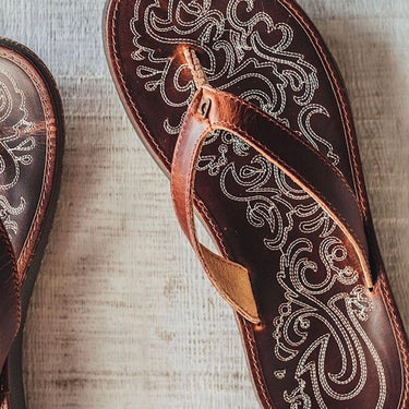 Close-up of handcrafted leather detailing on the OluKai Paniolo women's sandals showcasing premium craftsmanship and island-inspired artwork.