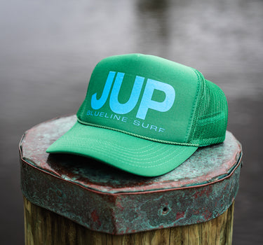 Otto JUP Hat in green and blue by Blueline Surf & Paddle Co., featuring blue gradient JUP logo on a foam mesh snapback, photographed in Jupiter, Florida.