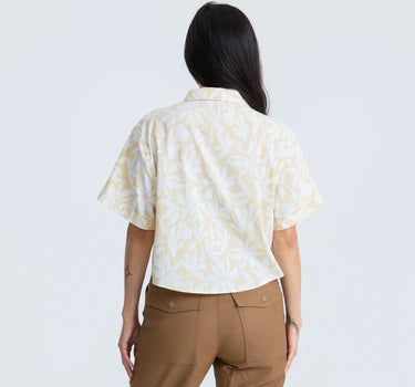 Person wearing a patterned shirt and brown pants on a white background