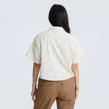 Person wearing a patterned shirt and brown pants on a white background