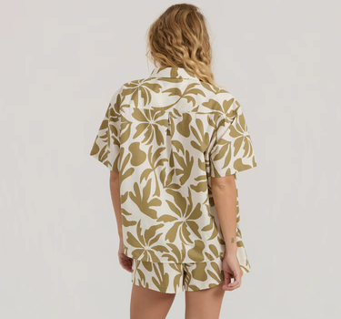 Person wearing a beige and white patterned shirt and shorts set on a plain background