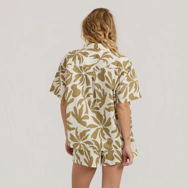 Person wearing a beige and white patterned shirt and shorts set on a plain background