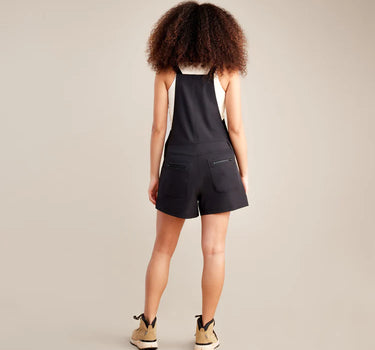 Person wearing a black sleeveless top and shorts set on a beige background