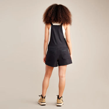 Person wearing a black sleeveless top and shorts set on a beige background