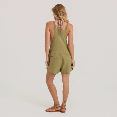 Woman wearing a green romper on a plain background