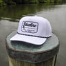 Blueline Rod & Reel Trucker Hat in white and black with vintage fishing patch and breathable mesh back.