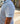 Person wearing a green striped polo shirt with 'BLUELINE' branding outdoors.
