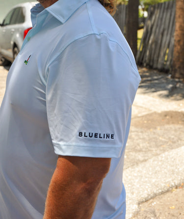 Person wearing a green striped polo shirt with 'BLUELINE' branding outdoors.