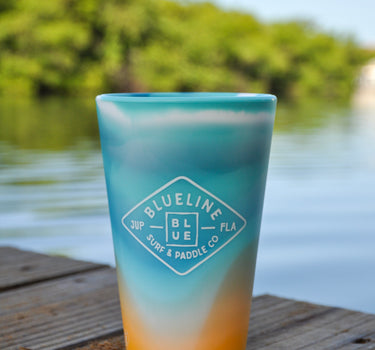 Silipint Silicone cup in shoreline color way sits on a wooden dock in Jupiter, Florida. The cup features a Blueline Surf and Paddle Co. diamond-shaped logo.