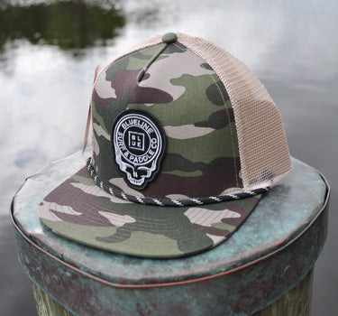 Army camo and khaki Skully rope trucker hat from Blueline Surf & Paddle Co. featuring custom skull artwork and coastal styling inspired by the Jupiter Florida saltwater lifestyle.