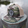 Army camo and khaki Skully rope trucker hat from Blueline Surf & Paddle Co. featuring custom skull artwork and coastal styling inspired by the Jupiter Florida saltwater lifestyle.