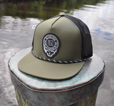 Olive and black Skully rope trucker hat from Blueline Surf & Paddle Co. featuring custom skull artwork and coastal performance styling inspired by the Jupiter Florida saltwater lifestyle.